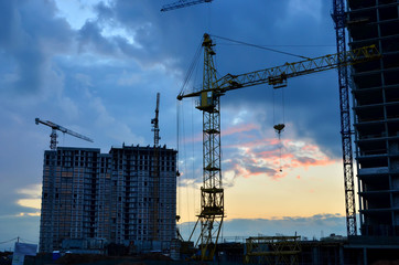 Tower cranes at construction site in the sunset sky  - Image