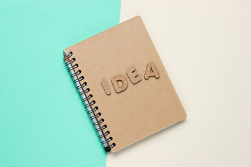I have an idea! Notebook with craft paper with word idea on colored pastel background. Top view