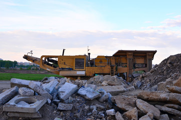 Fototapeta premium Mobile Stone crusher machine by the construction site or mining quarry for crushing old concrete slabs into gravel and subsequent cement production