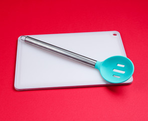 kitchen board with kitchen spoon on red background. Asian cuisine