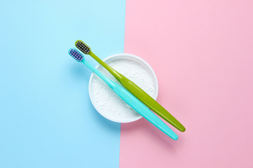 Two toothbrushes, tooth powder on pink blue pastel background. Minimalism oral hygiene concept. Top view