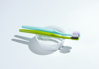 Two toothbrushes, tooth powder on white background. Minimalism oral hygiene concept.