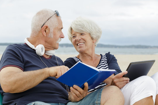 portrait of an happy mature couple reading a book outdoors