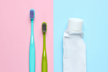Two toothbrushes with a tube of used toothpaste on pastel background. Top view