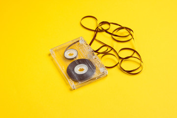 Music lover minimalism concept. Retro style 80s. Audio cassette with film on yellow paper background.