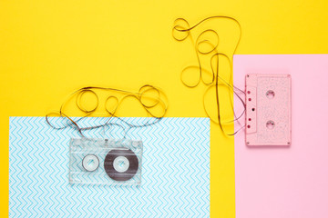 Music lover minimalism concept. Retro style 80s. Two audio cassettes with film on colored paper background.
