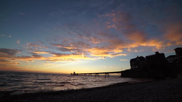 Beautiful vibrant sunset over ocean, with silhouette of pier