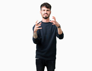 Fototapeta premium Young handsome man over isolated background Shouting frustrated with rage, hands trying to strangle, yelling mad