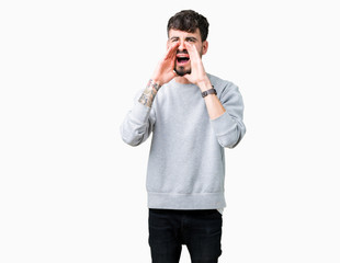 Young handsome man wearing sweatshirt over isolated background Shouting angry out loud with hands over mouth