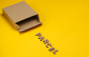 Postal services minimal concept. Empty cardboard box on a yellow paper background with a slogan...
