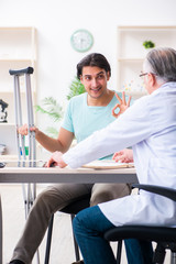 Fototapeta premium Young leg injured male patient visiting old doctor 