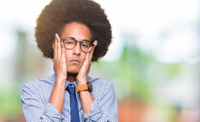 Fototapeta na wymiar Young african american business man with afro hair wearing glasses Tired hands covering face, depression and sadness, upset and irritated for problem