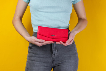 Minimal fashion concept. Woman holding a trendy red purse on yellow background. Crop photo, studio shot