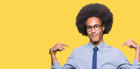 Young african american business man with afro hair wearing glasses looking confident with smile on face, pointing oneself with fingers proud and happy.