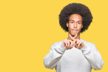 Young african american man with afro hair wearing sporty sweatshirt Rejection expression crossing fingers doing negative sign