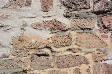 medieval wall made of red and brown irregular stones with mortar - background