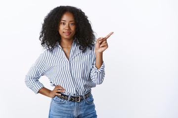 Girl customer made choice pointing sideways index finger wanna buy product smiling determined self-assured friendly-looking camera holding hand waist, standing white background - obrazy, fototapety, plakaty