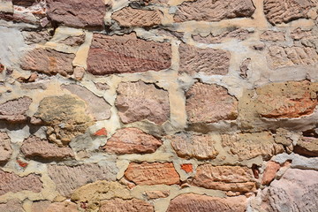 medieval wall made of red and brown irregular stones with mortar - background