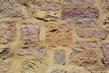 medieval wall made of red and brown irregular stones with mortar - background