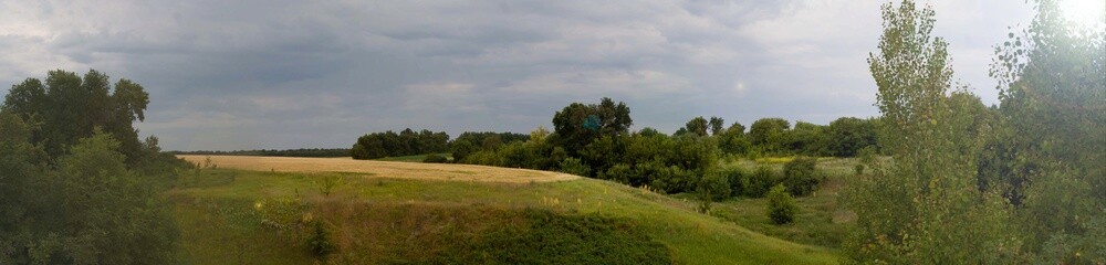 Fototapeta na wymiar rural landscape panorama with wheat field trees hills and bright sun