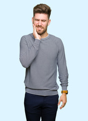 Young handsome man wearing stripes sweater touching mouth with hand with painful expression because of toothache or dental illness on teeth. Dentist concept.