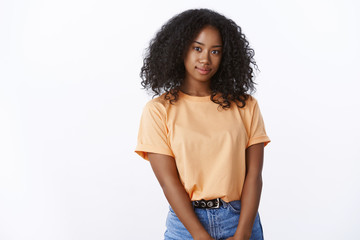 Attractive lovely african american girl university student curly-hairstyle wearing orange trendy t-shirt posing cute white background, smiling looking camera carefree joyful, expressing positivity