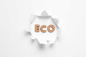 Word eco in a torn hole on white background. Minimalism ecology concept. Top view