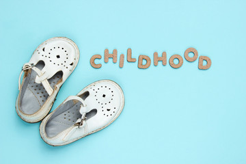 Children's leather sandals on blue background with word childhood
