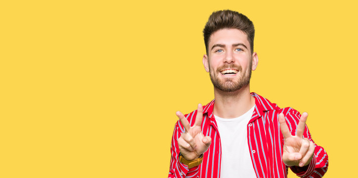 Young handsome man wearing red shirt smiling looking to the camera showing fingers doing victory sign. Number two.