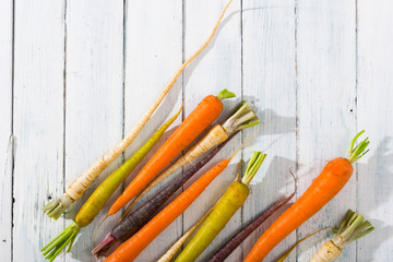 carrot variations in a row, on white wood table, top view