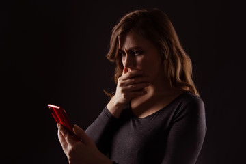 Obraz premium Girl with serious face holding phone and looking in it isolated