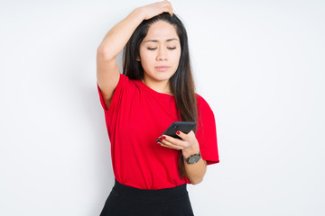 Young brunette woman using smartphone over isolated background stressed with hand on head, shocked with shame and surprise face, angry and frustrated. Fear and upset for mistake.