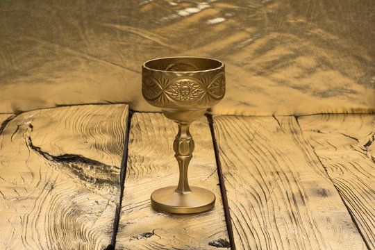 golden wine goblet isolated on golden wooden background