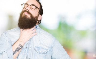 Young hipster man with long hair and beard wearing glasses Touching painful neck, sore throat for flu, clod and infection
