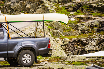 Car with canoe on top in mountains
