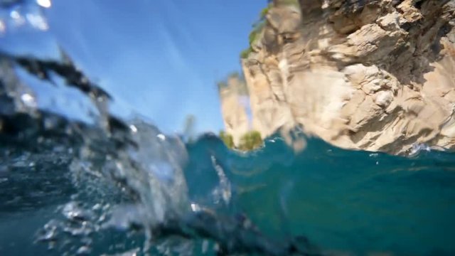 HALF UNDERWATER. View of the high cliffs of the Mediterranean sea. The wave beautifully covers the camera. The water is clean and clear