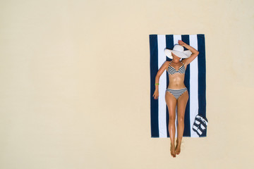Summer holiday fashion concept - tanning girl wearing sun hat at the beach on a white sand shot...