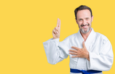 Handsome middle age senior man wearing kimono uniform over isolated background Swearing with hand...