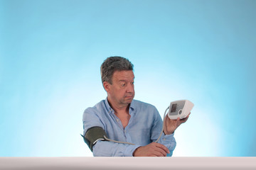 Ein Mann mit Blutdruckmessgerät erstaunt