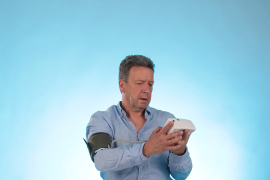 Ein Mann mit Blutdruckmessgerät liest Blutdruck ab