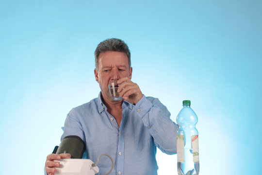 Ein Mann trinkt Wasser bei Blutdruckmessung