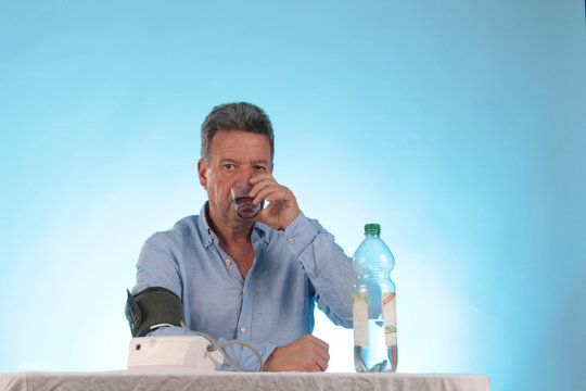 Ein Mann trinkt Wasser und misst Blutdruck