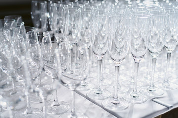 Welcome drink. Rows of empty wine or champagne glasses close up. glass goblets on the white table. Empty crystal wineglass. glass goblet on a high leg. Restaraunt bar concept