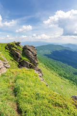 path through the edge of a mountain. beautiful summer landscape in mountains. big rock on the grassy slope in front. sunny weather with clouds on the sky