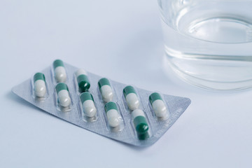 pills in blister isolated on white background with glass of water