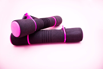 Two plastic coated dumbells on pink background.