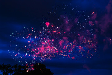 Inexpensive fireworks over the city red, pink and white. Bright and shiny.  For any purpose. Celebration concept.