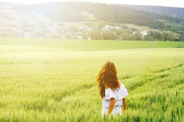 Happy beautiful woman in the meadow. Beautiful carefree woman in the fields. Young woman and young wheat.