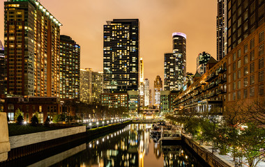 Fototapeta na wymiar Chicago city illuminated buildings in the evening. Reflections on the river canal