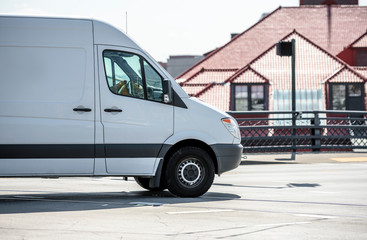Fototapeta na wymiar White compact minivan for small business and local deliveries running on the city street